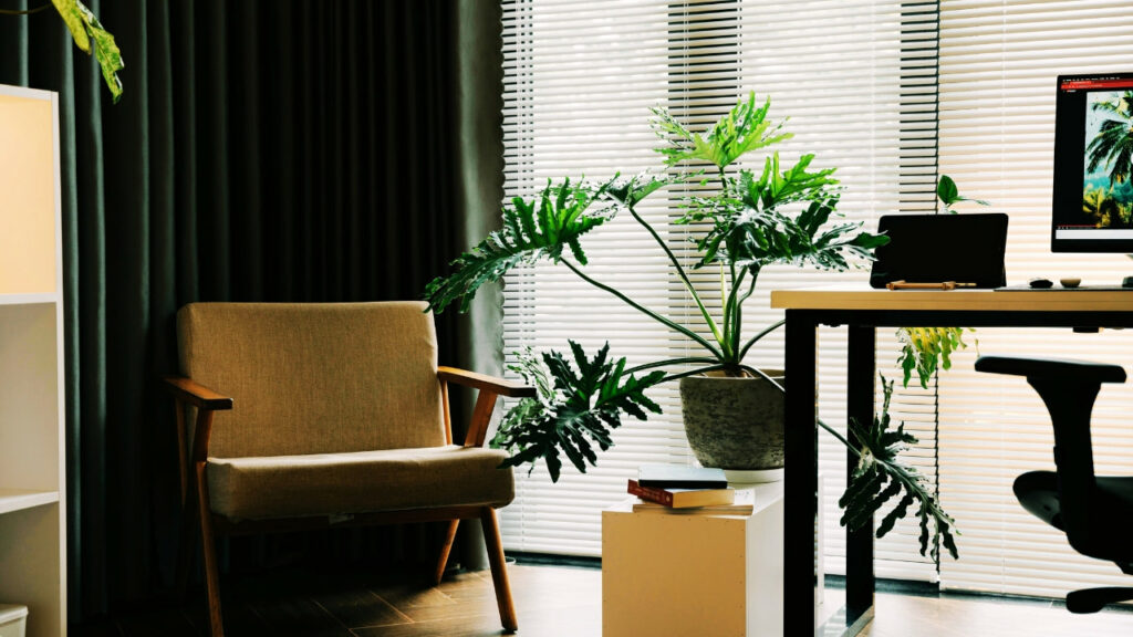 Ambiente criativo com poltrona retrô, plantas grandes e iluminação suave.