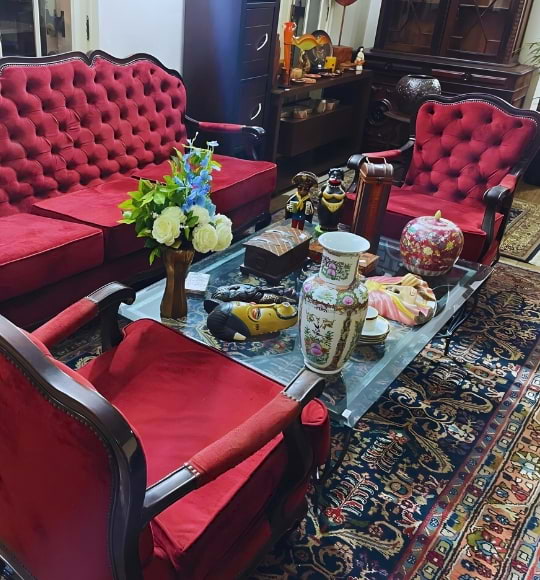 Conjunto de sofá, poltronas e mesa de centro com peças de decoração vintage, tapete oriental e porcelanas em exposição na Coar